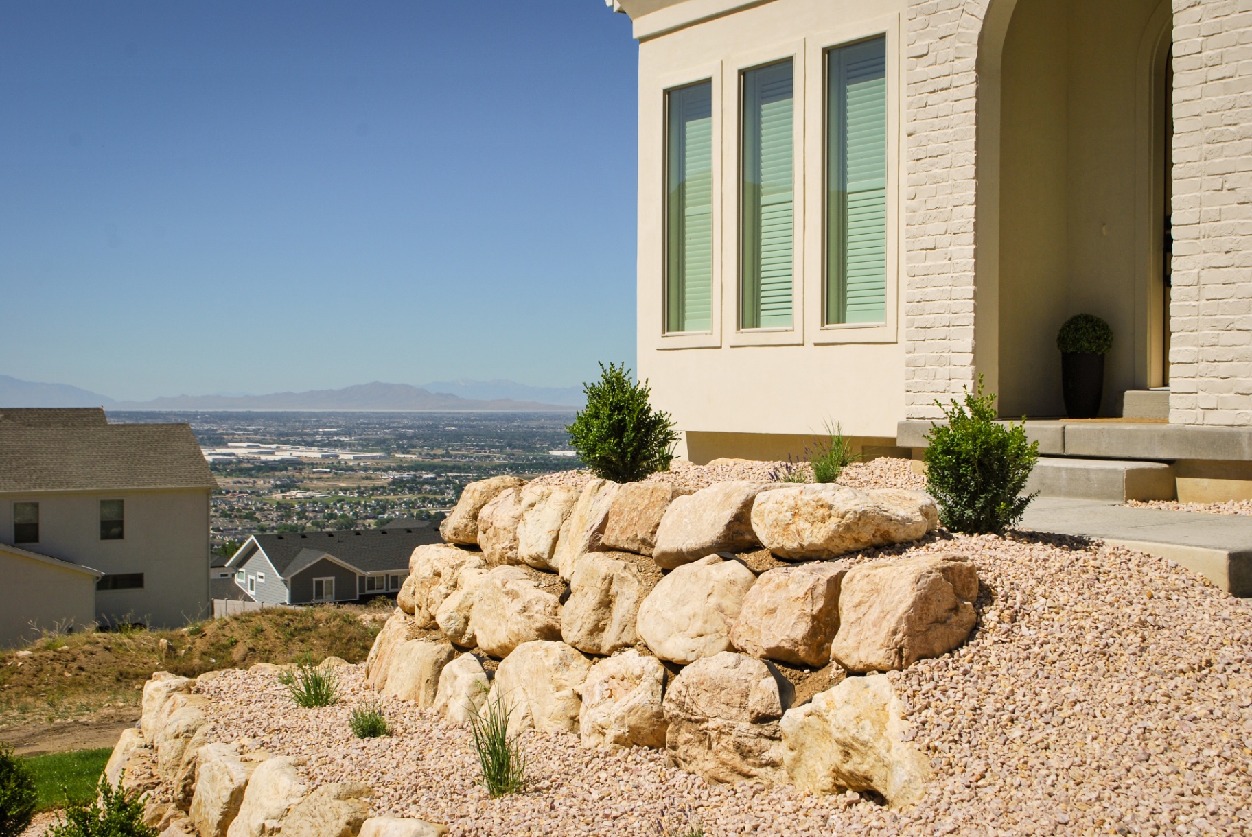 Stacked boulder retaining wall at a hillside home with valley view