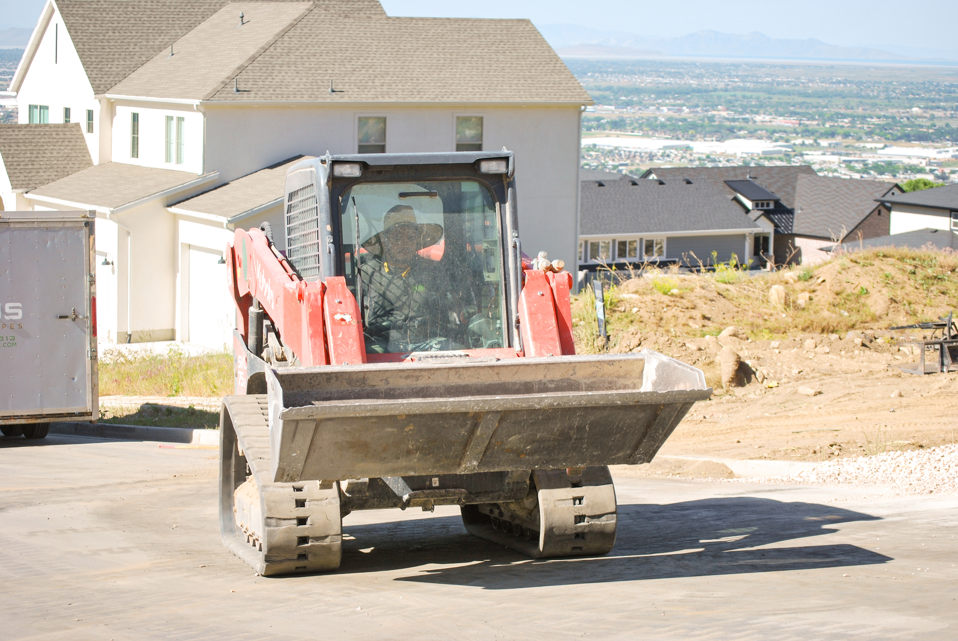 Operator running a skid steer on a hillside build