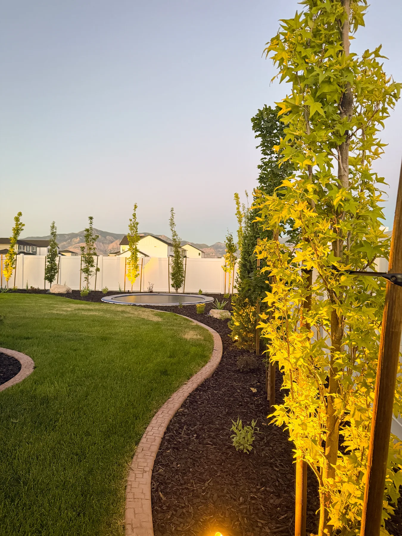 Low-voltage landscape lighting installation at dusk